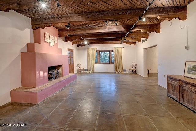 unfurnished living room featuring a fireplace, beamed ceiling, rail lighting, dark tile patterned floors, and wood ceiling