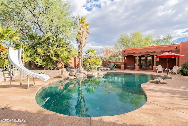 view of swimming pool with a water slide and a patio area