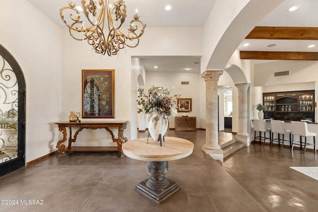 foyer entrance with beam ceiling, decorative columns, and a chandelier