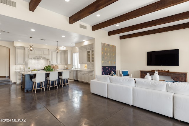 living room with an inviting chandelier, beamed ceiling, and sink