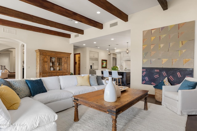 living room with beam ceiling, wood-type flooring, and an inviting chandelier