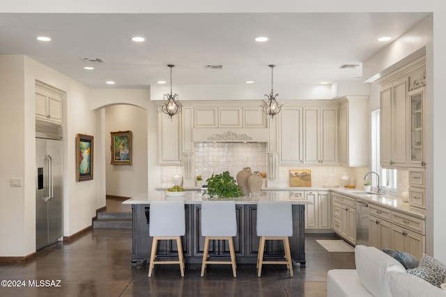 kitchen with a kitchen island, cream cabinetry, hanging light fixtures, sink, and appliances with stainless steel finishes