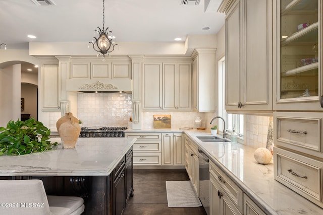 kitchen with light stone countertops, cream cabinets, sink, decorative light fixtures, and custom range hood