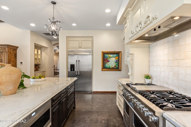 kitchen with decorative backsplash, high quality appliances, light stone countertops, dark brown cabinetry, and custom exhaust hood