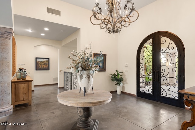 entryway featuring a towering ceiling, french doors, and a notable chandelier