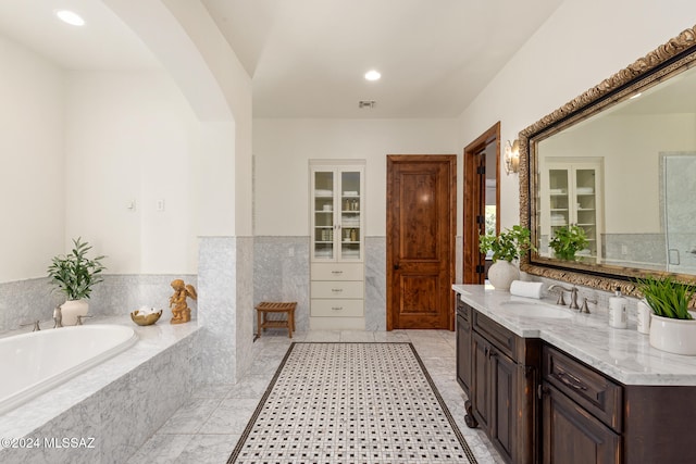 bathroom featuring vanity, tile patterned floors, and tiled bath