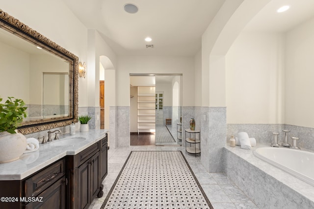 bathroom with vanity and tiled bath