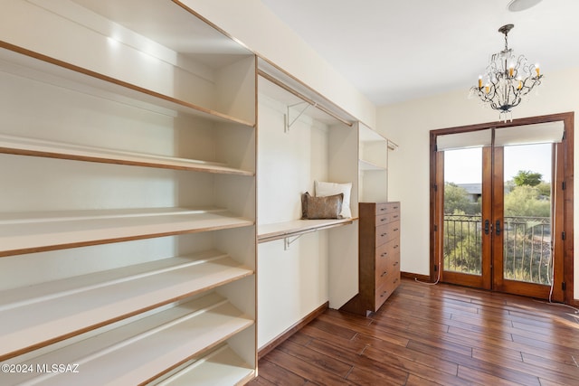 spacious closet with french doors, an inviting chandelier, and dark hardwood / wood-style floors