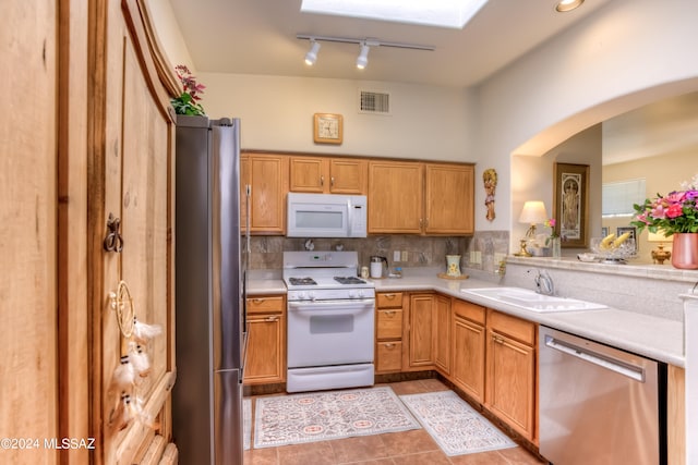 kitchen featuring appliances with stainless steel finishes, sink, light tile patterned floors, and backsplash