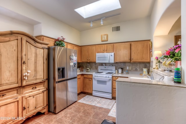 kitchen with a skylight, tasteful backsplash, white appliances, light tile patterned floors, and track lighting