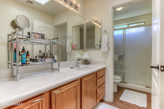 bathroom with tile patterned floors, vanity, a shower with door, and toilet