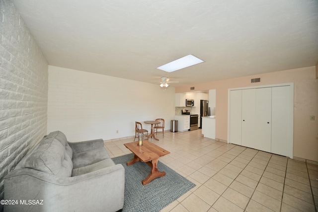 tiled living room featuring a skylight and ceiling fan