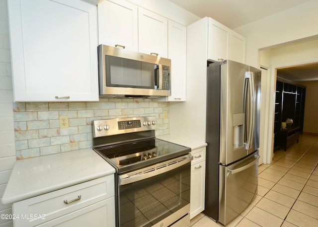 kitchen featuring white cabinets, stainless steel appliances, tasteful backsplash, and light tile patterned flooring