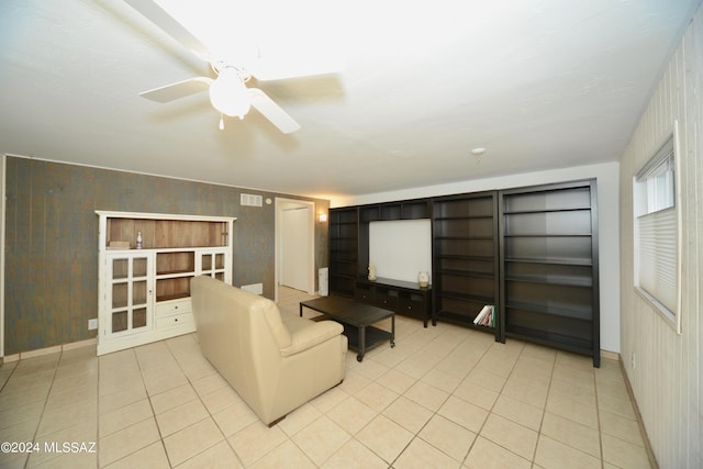 unfurnished living room featuring ceiling fan, light tile patterned floors, wooden walls, and built in shelves