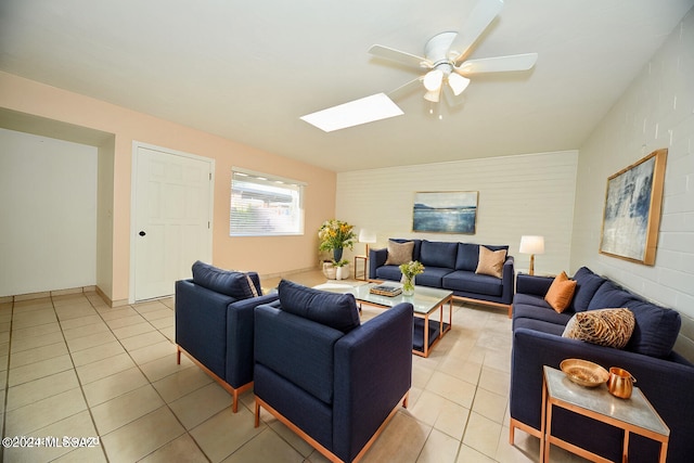 living room with a skylight, ceiling fan, and light tile patterned floors