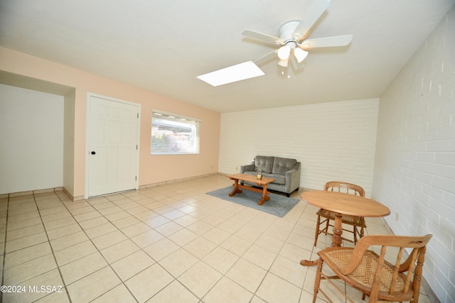 sitting room featuring ceiling fan, brick wall, and light tile patterned flooring