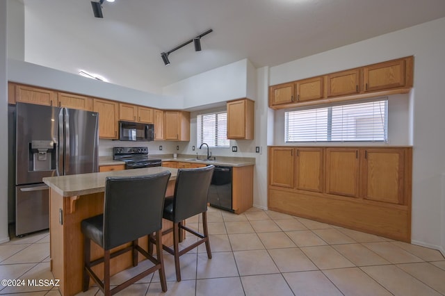 kitchen featuring rail lighting, a kitchen breakfast bar, a kitchen island, black appliances, and sink