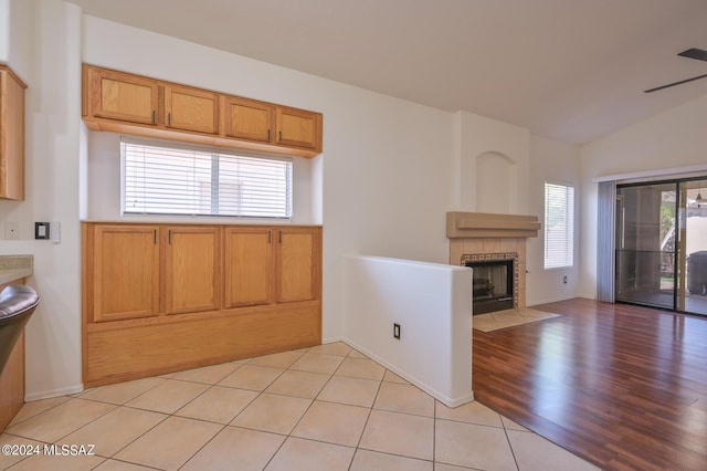 kitchen featuring a wealth of natural light, light tile patterned floors, lofted ceiling, and a fireplace