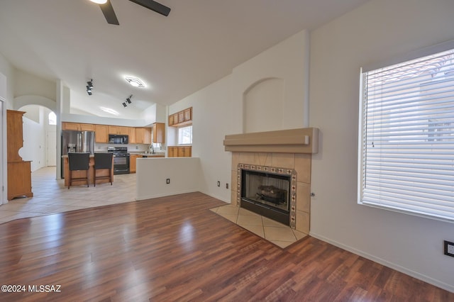 unfurnished living room featuring light hardwood / wood-style floors, plenty of natural light, ceiling fan, and a tiled fireplace