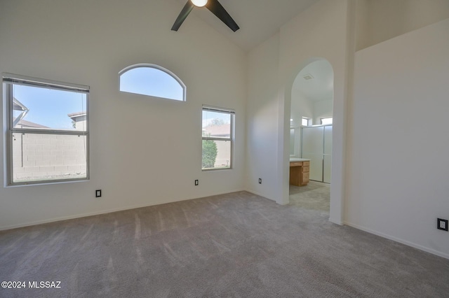 unfurnished room featuring high vaulted ceiling, light colored carpet, ceiling fan, and a healthy amount of sunlight