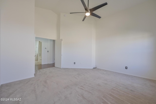 carpeted spare room with ceiling fan and high vaulted ceiling