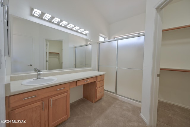 bathroom with vaulted ceiling, a shower with shower door, and vanity