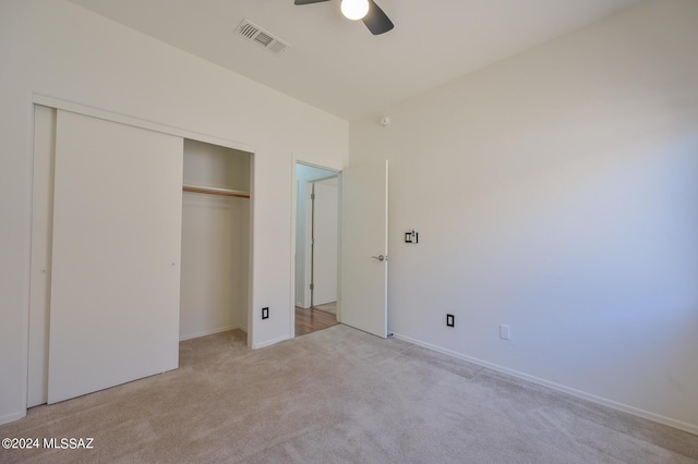 unfurnished bedroom featuring ceiling fan, light colored carpet, and a closet