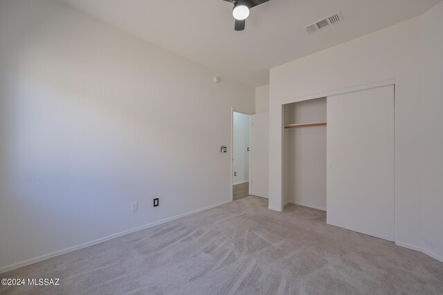 unfurnished bedroom featuring ceiling fan, a closet, and light carpet