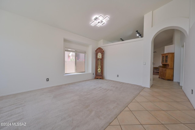 unfurnished room with lofted ceiling and light tile patterned flooring