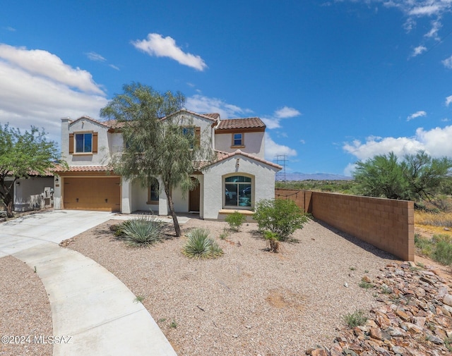 mediterranean / spanish-style house featuring a tiled roof, stucco siding, fence, an attached garage, and driveway