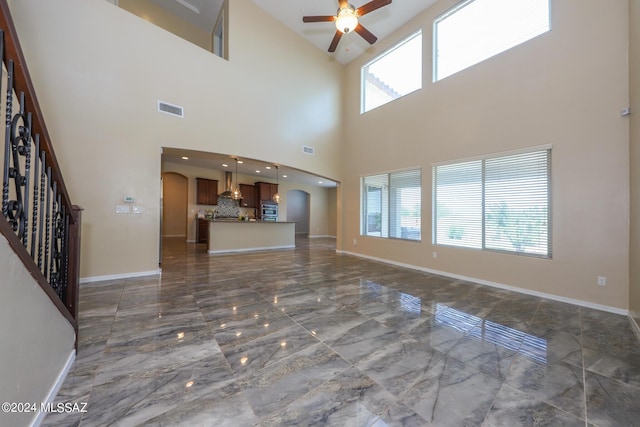 unfurnished living room featuring arched walkways, visible vents, marble finish floor, and a ceiling fan