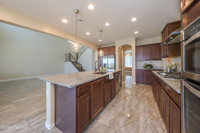 kitchen featuring visible vents, arched walkways, a sink, an island with sink, and stainless steel appliances