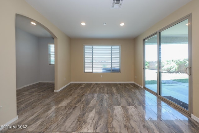 empty room with visible vents, baseboards, and arched walkways