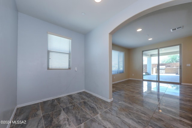 spare room with arched walkways, baseboards, visible vents, and recessed lighting
