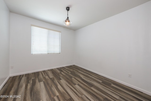 unfurnished room with baseboards and dark wood-style floors
