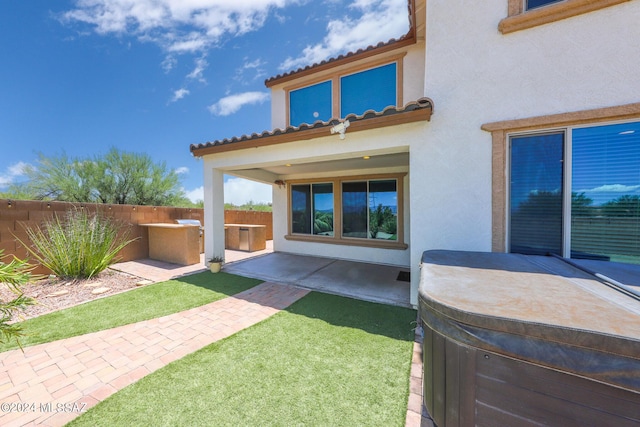 back of house with a tile roof, fence, a patio, and stucco siding