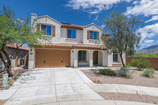 mediterranean / spanish-style house with concrete driveway, stucco siding, an attached garage, a tiled roof, and fence