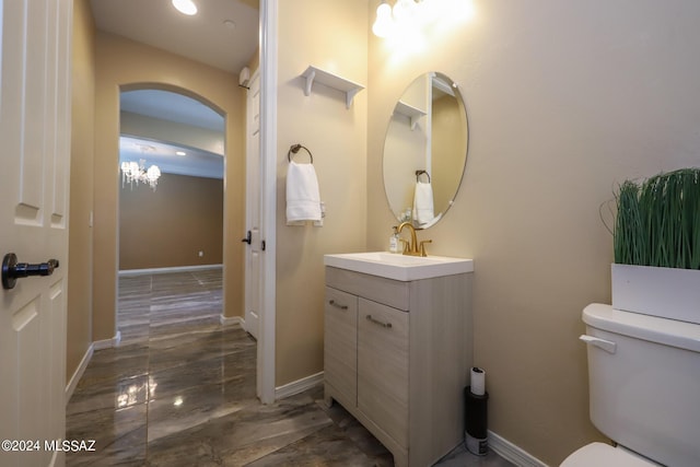 bathroom with toilet, vanity, baseboards, and recessed lighting