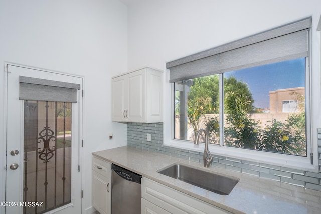 kitchen featuring tasteful backsplash, sink, light stone countertops, stainless steel dishwasher, and white cabinetry