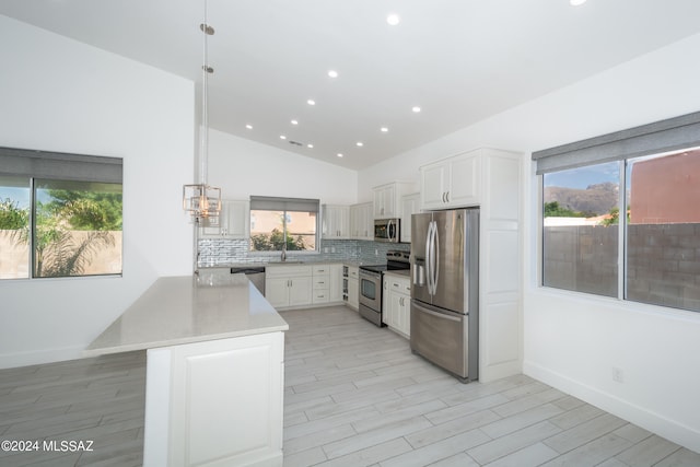 kitchen featuring sink, decorative light fixtures, backsplash, white cabinetry, and appliances with stainless steel finishes