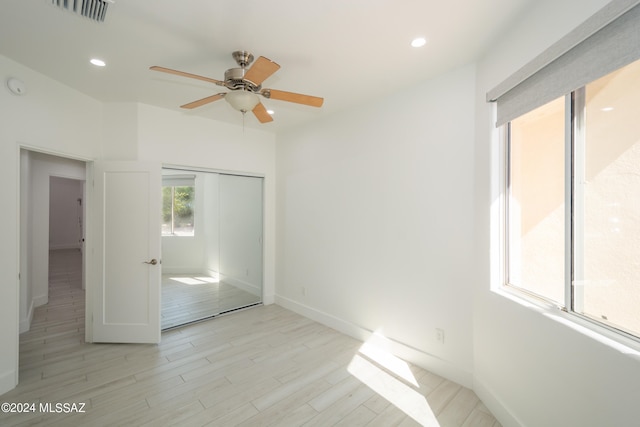 unfurnished bedroom with light wood-type flooring, ceiling fan, and a closet