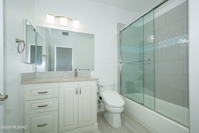 full bathroom with vanity, toilet, and combined bath / shower with glass door