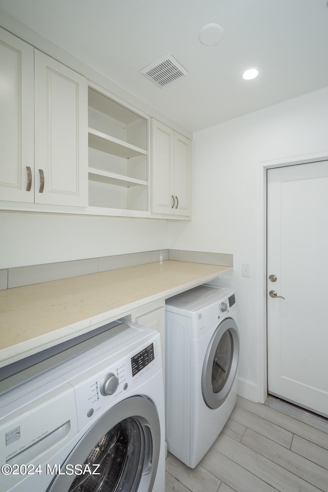 laundry room with washer and dryer, cabinets, and light hardwood / wood-style flooring