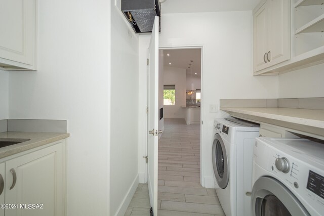 washroom featuring washer and dryer, cabinets, and light wood-type flooring