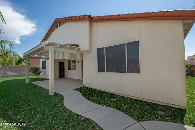 rear view of property with a patio and a lawn