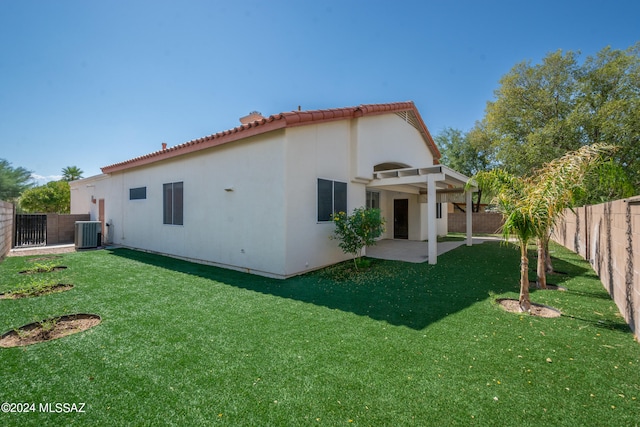 rear view of property featuring cooling unit, a yard, and a patio area