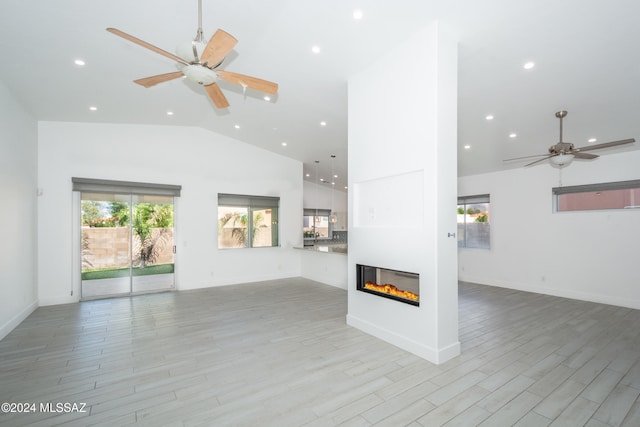 unfurnished living room with high vaulted ceiling, light wood-type flooring, and ceiling fan