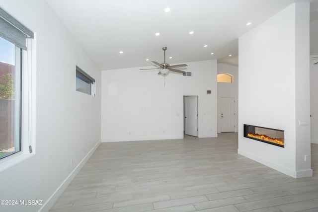 unfurnished living room featuring ceiling fan, light hardwood / wood-style floors, and high vaulted ceiling