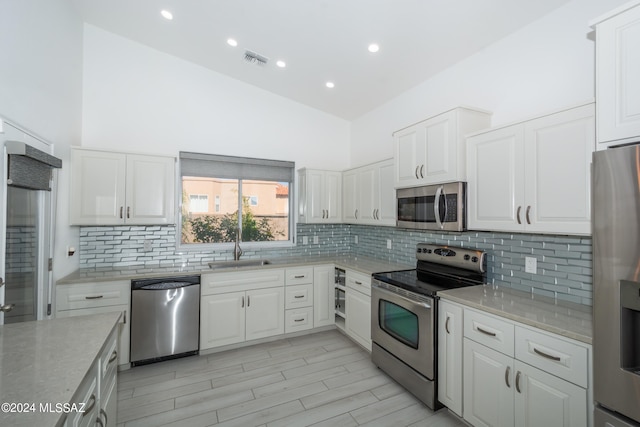 kitchen with appliances with stainless steel finishes, sink, tasteful backsplash, and white cabinetry