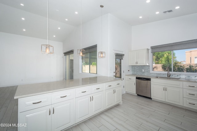 kitchen featuring hanging light fixtures, sink, stainless steel dishwasher, high vaulted ceiling, and white cabinetry